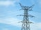 Tall metal electricity pylon with multiple cables against a blue cloudy sky