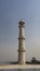 The tall minaret of the ancient Taj Mahal against a clear blue sky.