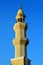 A tall minaret with golden ornament of a mosque against blue sky, minaret or tower aspiring to heaven