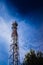 A tall modern communications tower provides telecommunications service to a city, negative space on blue background