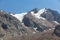 A tall mountain stone covered with snow and a blue sky