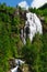 Tall norwegian waterfall and coniferous forest