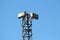 Tall partially rusted strong metal tower with two old antennas mounted on top on clear blue sky back