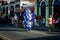 Tall person in variegated costume pass by city street at dominican carnival