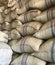 A tall pile of burlap sacks located in the exporter\'s warehouse.