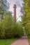 A tall pipe made of brown bricks against the sky and trees