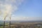 Tall pipes of power plant, white smoke on rural landscape and blue sky copy space background