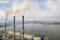 Tall pipes of power plant, white smoke on rural landscape, lake water and blue sky copy space background