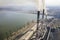 Tall pipes of power plant, white smoke on rural landscape, lake water and blue sky copy space background