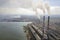 Tall pipes of power plant, white smoke on rural landscape, lake water and blue sky copy space background