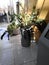 Tall plants with big leaves hanging over tall wooden pot.