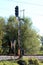 Tall railway tracks traffic light mounted on strong metal pole next to old dilapidated dirty sign and safety fence