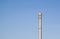 Tall rusty silver pole on a clear blue sky background