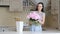 A tall slender European-looking brunette puts beautiful pink fragrant peonies in a vase.