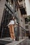 Tall stylish girl with oversized jacket posing near the railing and steps on the city background