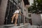 Tall stylish girl with oversized jacket posing near the railing and steps on the city background