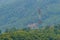 A tall telecommunication tower is standing in amid the green val