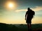 Tall tourist with poles in hand. Sunny evening in rocky mountains. Hiker with big backpack stand on rocky view point above misty v