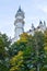 Tall tower on ancient Neuschwanstein castle over trees in autumn with sky on background