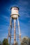 Tall water tower with cloudy blue sky background