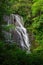 Tall Waterfall surrounded by green forest in summer