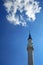 A tall white minaret of a Muslim mosque against the sky.