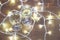 Tall wine glasses with bubbly drink for celebration toast wrapped in a Christmas light. Close up