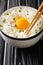 Tamago kake gohan is a popular Japanese breakfast food consisting of cooked Japanese rice topped with raw egg close up in the bowl