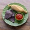 Tamale with blue corn tortillas and tomato sauce top view