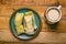 Tamales de elote and atole on a wooden table.