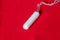 Tampon on a red background, close up, top view, menstrual period