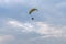 A tandem motor paraglider flies through the evening cloudy sky with a pilot and a passenger.