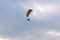 A tandem motor paraglider flies through the evening cloudy sky with a pilot and a passenger
