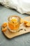 tangerine cocktail with ice in a low highball glass and tangerine on a wooden olive Board on a gray textured background