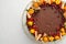 Tangerine Homemade Cake Decorated with Chocolate Icing and Mandarines, Pomegranate, White Cream. Top View. Flat Lay. White backgro