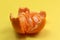 Tangerine peeled with the skin lies on a yellow background