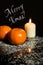 Tangerines and Candle on icing sugar, black stone and black back