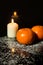 Tangerines and Candle on icing sugar, black stone and black back