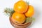 Tangerines in a clay pot. Between them are branches of blue spruce. On white background