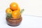 Tangerines in a clay pot. Between them are branches of blue spruce. On white background