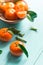 Tangerines with green leaves in a wooden bowl