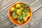 Tangerines with green leaves in a wooden bowl on a wooden background