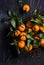 Tangerines with green leaves in wooden box on dark background