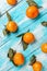 Tangerines with leaves lie on a wooden blue table. Strips of boards on the diagonal. Vertical orientation