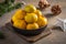 Tangerines or mandarines and ripe slices in bamboo bowl on wooden board, next to Christmas tree branch