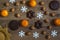 Tangerines, nuts, gingerbread and spiced biscuits, star-like snowflakes, sun disordered on rustic wooden floor background