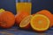 Tangerines, oranges, a glass of orange juice and manual citrus squezeer on blue wooden background. Oranges cut in half
