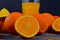 Tangerines, oranges, a glass of orange juice and manual citrus squezeer on blue wooden background. Oranges cut in half