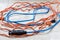 Tangled blue and orange extension cords on white background