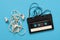 Tangled earphones and retro music cassette isolated on blue background